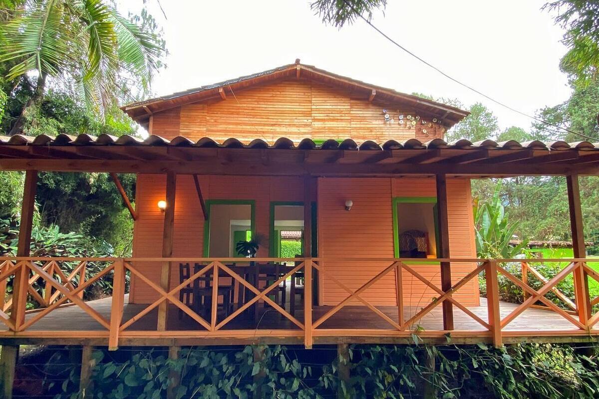 A wooden cabin with a porch, surrounded by lush greenery.