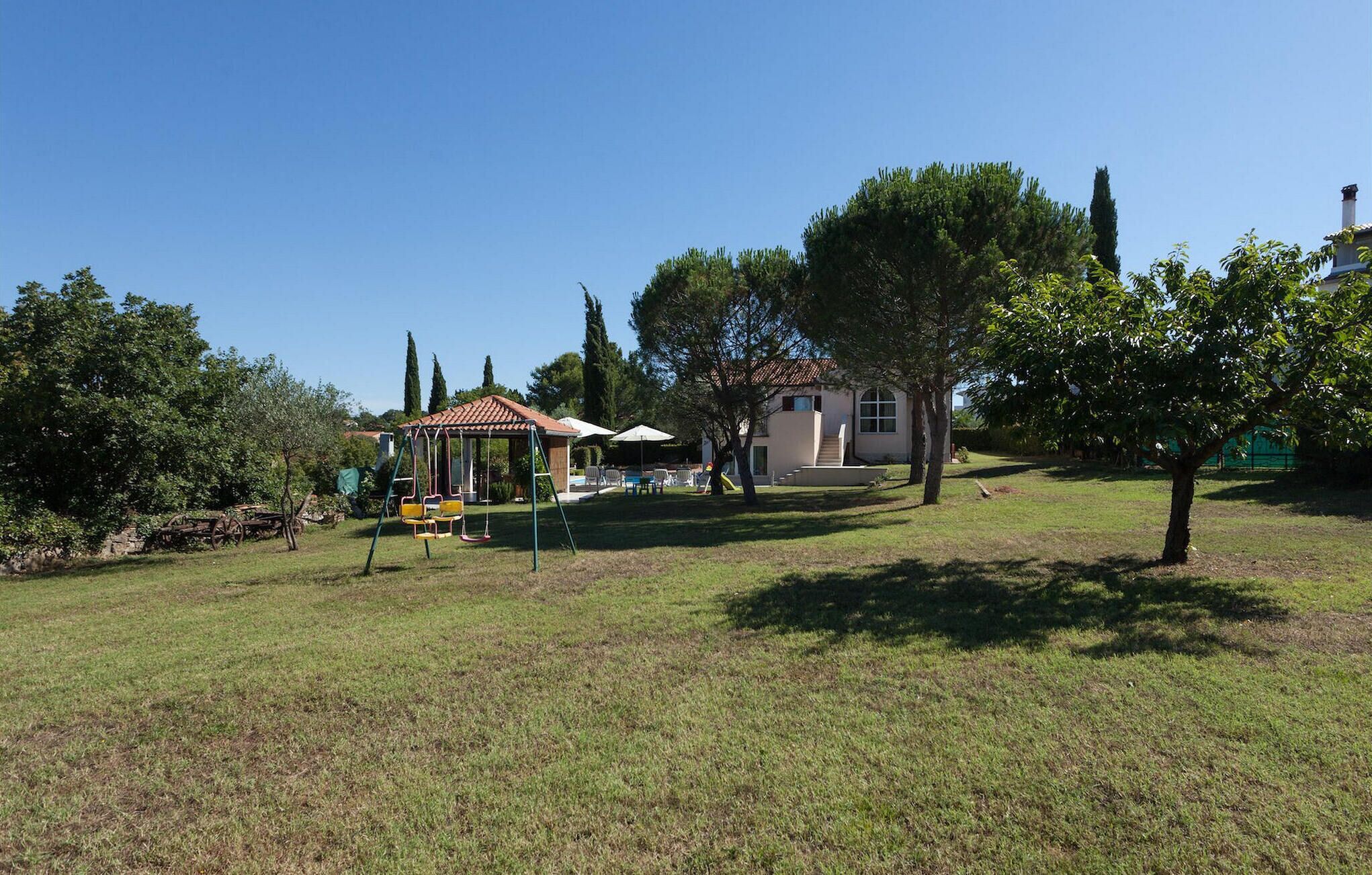 A residential area with a house, a swing set, and a small garden.