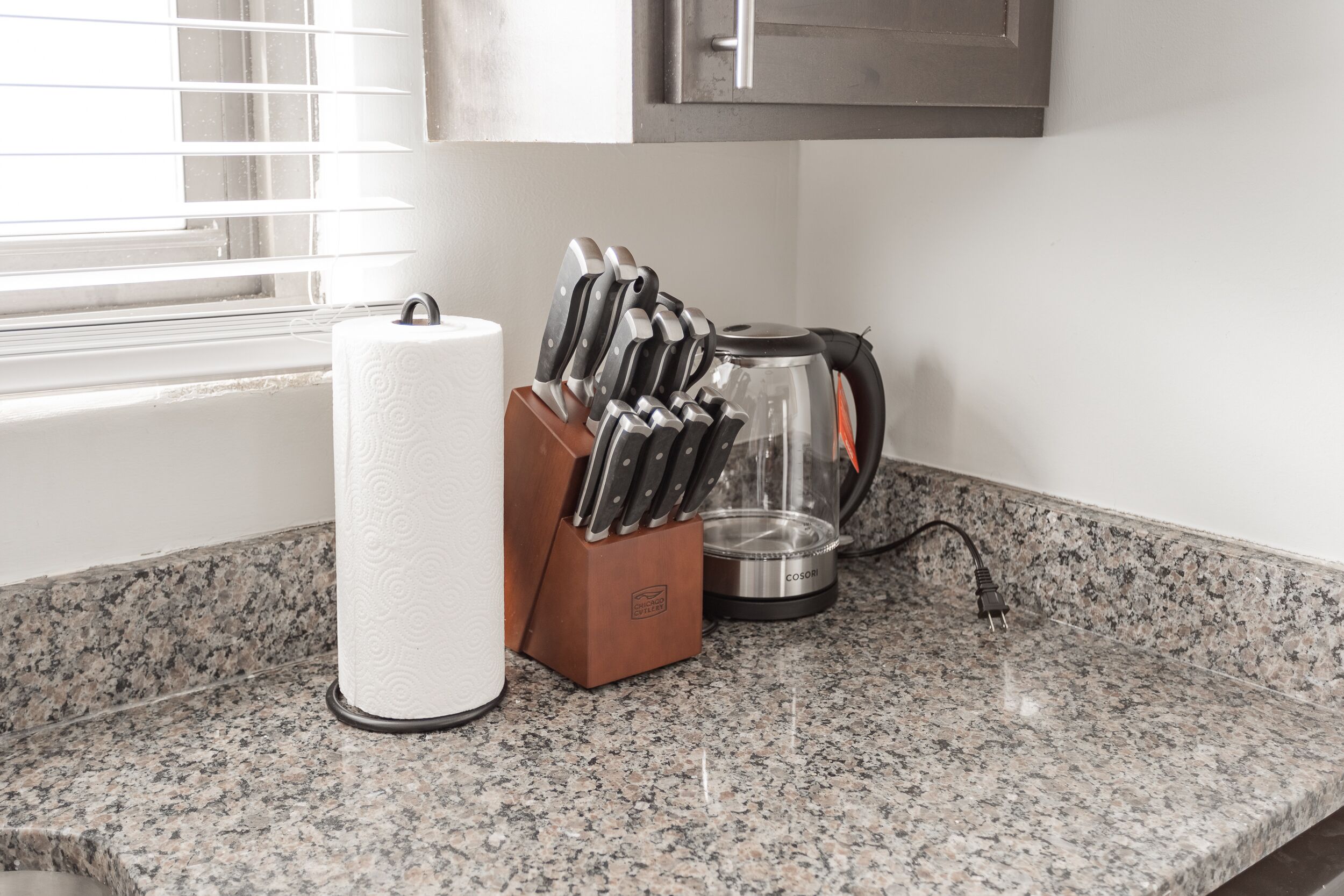 A kitchen counter with a paper towel holder, a knife block, and a coffee maker.