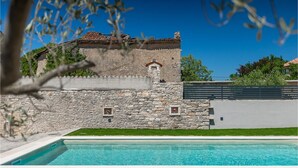 Ein Gebäude aus Stein mit einem Pool davor.