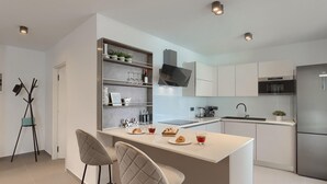 Eine moderne Küche mit einer zentralen Kochinsel, Barhocker und einem integrierten Weinkühlschrank.
