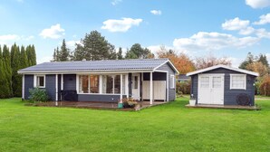 A two-story house with a covered porch and a separate garage. - Nice home in Bogø By with WiFi (Bogø By)