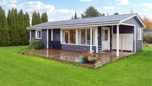 A single-story house with a covered porch, a deck, and a garage. - Nice home in Bogø By with WiFi (Bogø By)