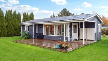 Et etplanshus med en overdækket veranda, en terrasse og en garage.