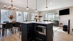 A modern kitchen with a central island, black cabinetry, stainless steel appliances, and pendant lighting.