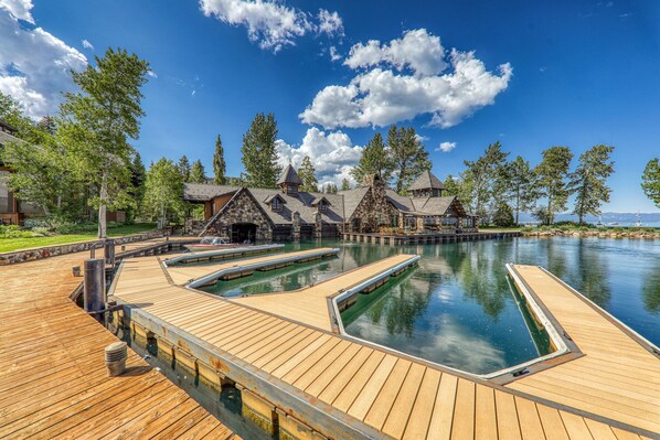 A wooden deck with a swimming pool, surrounded by lodge-style buildings with sloped roofs.