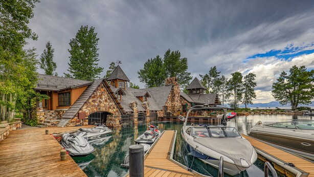 A marina with boats docked, a wooden deck, and stone buildings with steep roofs. - Fleur Du Lac 16 By Tahoe Getaways - Lakefront Monthly Rental with Pool, Tennis, Gym, Boat Slip (Homewood)