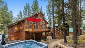 Een houten chalet met een jacuzzi, een terras en een trap die naar een balkon leidt.