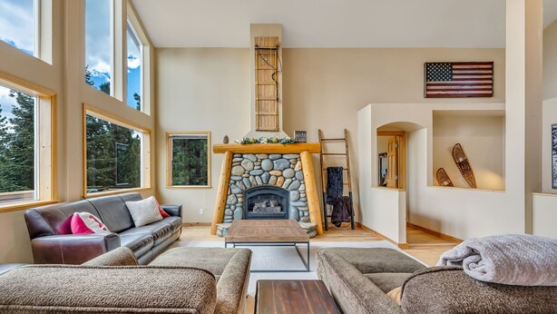 A spacious living room with a stone fireplace, large windows, and a cozy seating area.