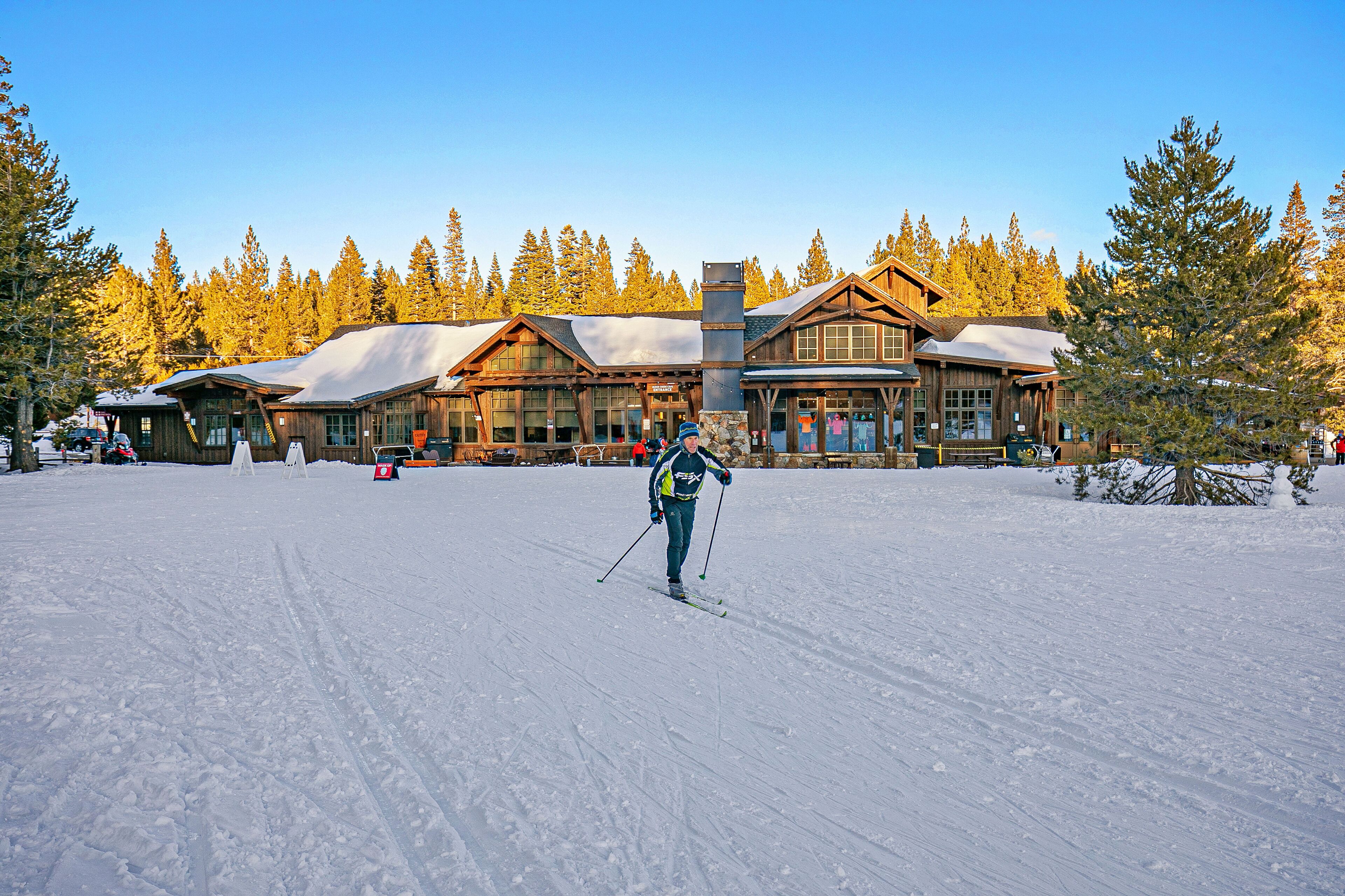 A lodge with a large wooden structure, ski tracks, and a snowy landscape.