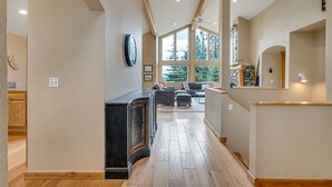 A spacious hallway with wooden flooring, a built-in piano, and a seating area with a sofa and ottoman.
