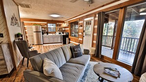 A cozy living room with a sofa, a coffee table, and a kitchen in the background. - Romantic Getaway•Views•Hot Tub•Fire Place•Seclusion (Sevierville)