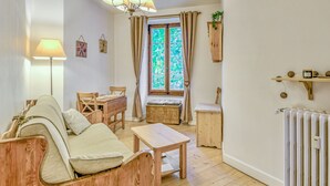 Una sala de estar acogedora con un sofá, una mesa de madera, una mesa de comedor y una ventana con cortinas.