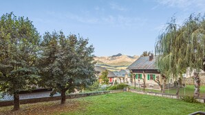 Un patio con césped, un árbol, un muro de piedra y un edificio con una puerta verde.