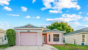 A residential house with a pink garage door, a small attached garage, and a well-maintained lawn.