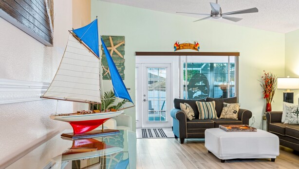A modern living room with a glass coffee table, a sofa, and a ceiling fan.
