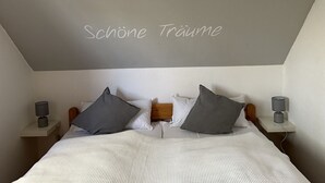 Un dormitorio con cama, dos mesitas de noche, dos lámparas y un techo con el texto "Schöne Träume".