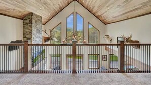 Ein geräumiger Innenraum mit hoher Decke, Steinwand und großen Fenstern mit Blick ins Freie.
