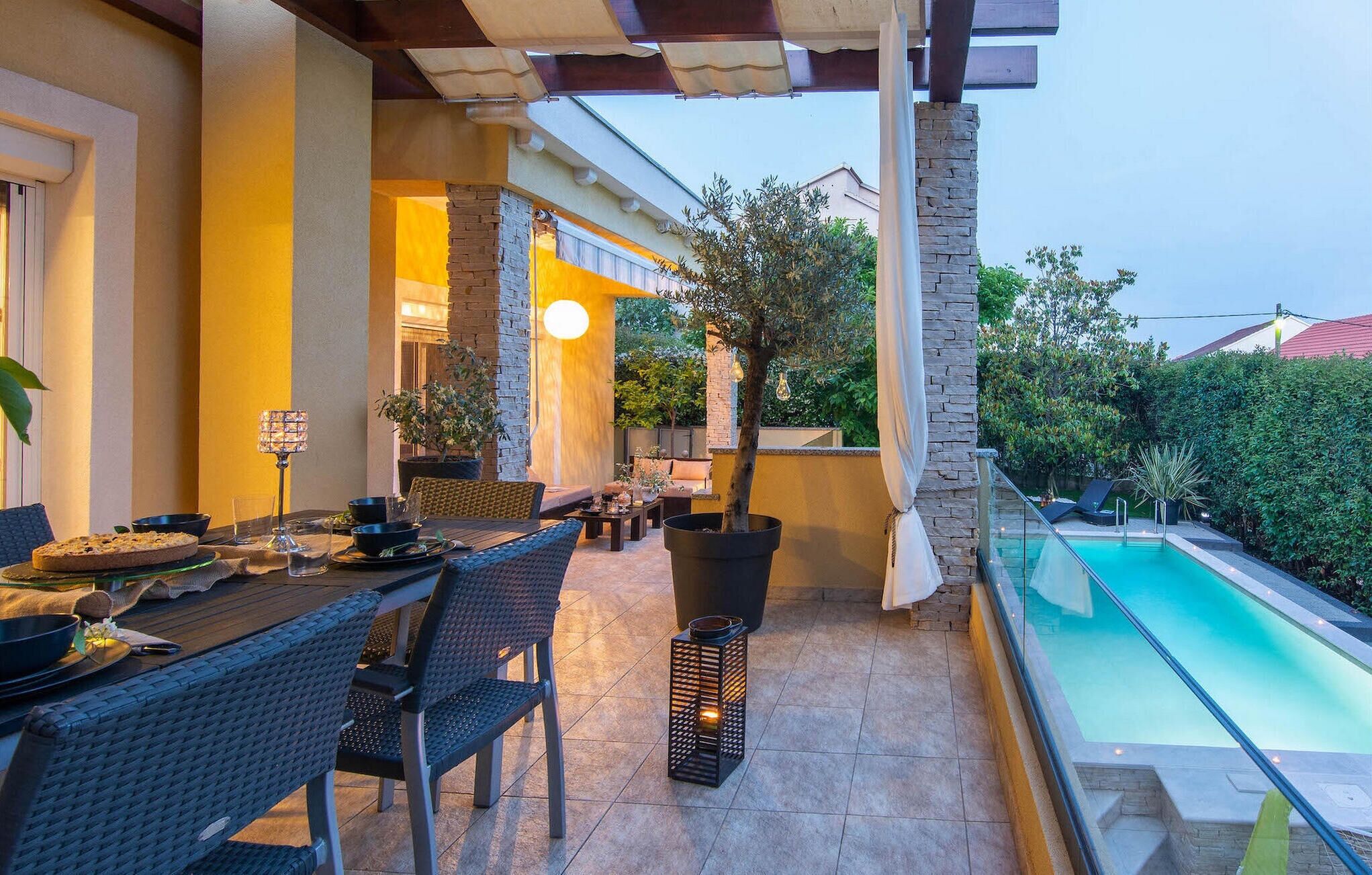 An outdoor dining area with a pool, stone walls, and potted plants.