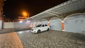 Un auto blanco estacionado en un área de estacionamiento techada con piso de piedra con diseño.