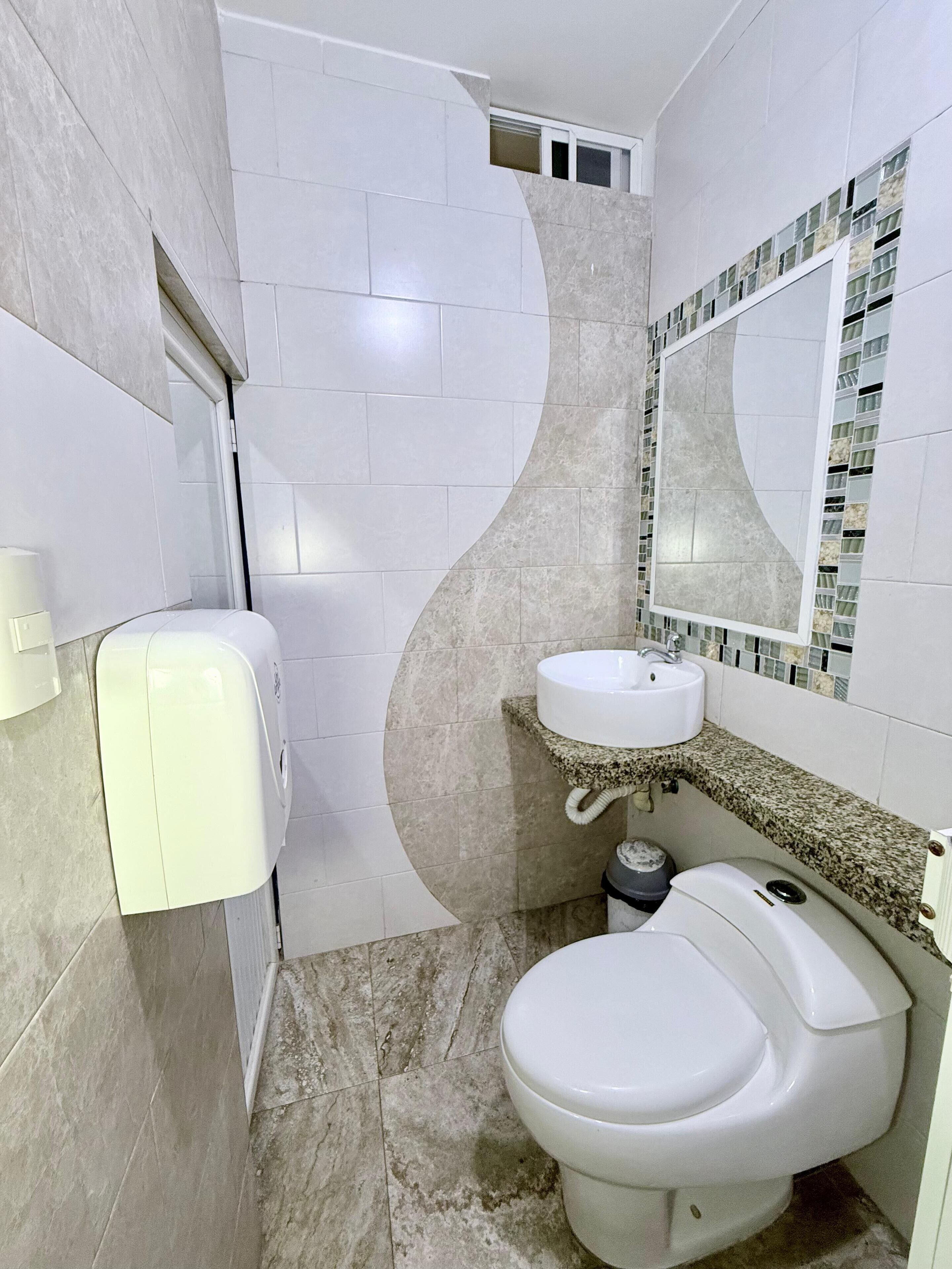 A bathroom with a toilet, sink, and hand dryer.