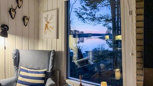 A room with a large window overlooking a lake, a striped chair, and wall-mounted animal skulls. - Stunning home in Skånes Fagerhult (Skånes Fagerhult)