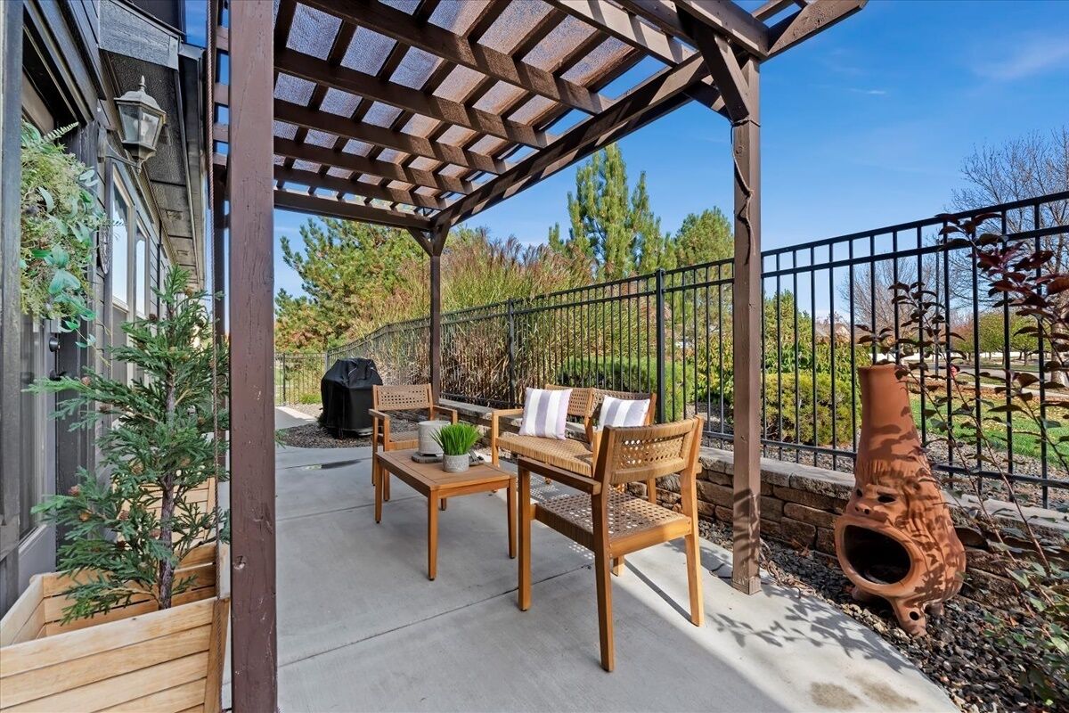 Ein überdachter Patio-Bereich mit Holzmöbeln, einem Grill und einem Zierkübel.