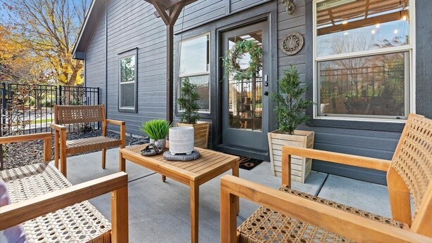 Eine überdachte Terrasse mit Holzmöbeln und Kübelpflanzen.