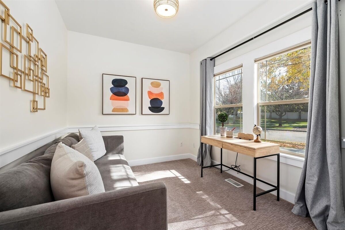 A modern living room with a grey sofa, two abstract paintings, a wooden side table with a globe, and a window with curtains.