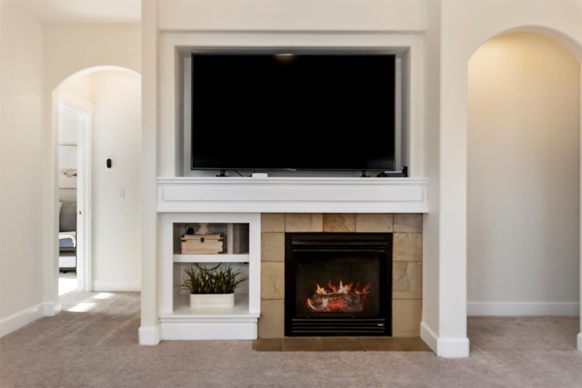 A living room with a fireplace, a mounted television, and a bookshelf.