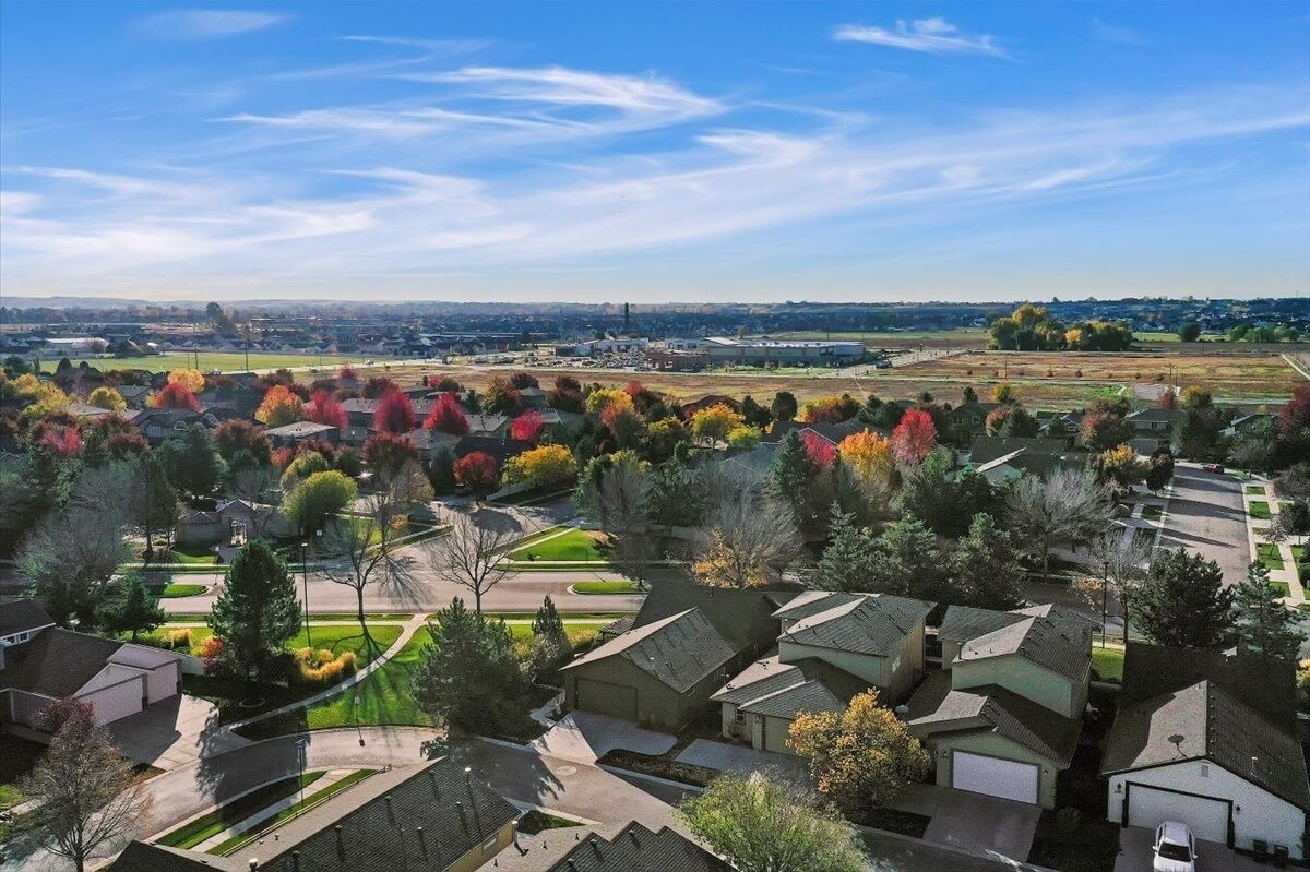 Un quartier résidentiel avec des maisons, un parc et une zone industrielle située à distance.