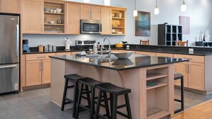 Eine moderne Küche mit Holzausstattung, einer zentralen Kochinsel mit Hockern, einer eingebauten Mikrowelle und Pendelleuchten.