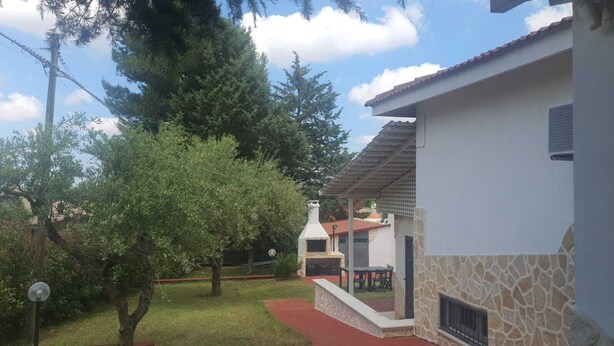 Una casa con facciata in pietra, tetto rosso e un patio con tavolo e sedie.