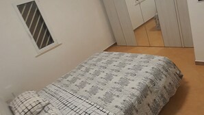 Una camera da letto con un letto, una finestra con persiane, un armadio e una lampada a soffitto.
