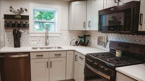 A kitchen with white cabinets, a stainless steel dishwasher, a gas stove, and a microwave.