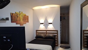 Una camera da letto con un letto, lampade da comodino, una TV e un tavolino in legno.