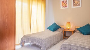 A bedroom with two beds, a nightstand with a lamp, and two framed pictures on the wall. - Holiday Home 'Casa Karen' with Sea View, Private Terrace and Wi-Fi (Tossa del Mar)