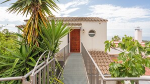 A building with a tiled roof, a wooden door, and a metal staircase leading to a balcony. - Holiday Home 'Casa Karen' with Sea View, Private Terrace and Wi-Fi (Tossa del Mar)