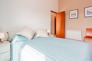 Une chambre à coucher comprenant un lit, une table de chevet, une lampe et une porte donnant sur une autre pièce.