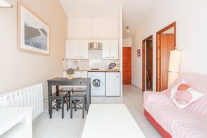 Um espaço compacto para viver, com cozinha americana, área de refeições e quarto.