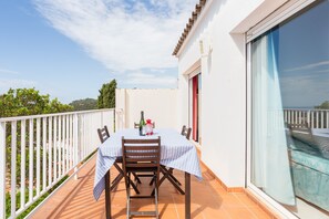 Un balcon avec une table dressée pour deux personnes, une chaise et une bouteille de vin.