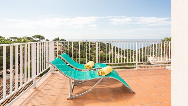 A balcony with two green lounge chairs, one with a towel. - Holiday Home 'Casa Karen' with Sea View, Private Terrace and Wi-Fi (Tossa del Mar)