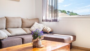 A living room with a sofa, a wooden coffee table, and a window with curtains. - Holiday Home 'Casa Martini' with Sea View and Private Terrace (Tossa del Mar)