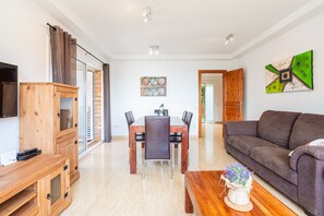 Una sala de estar moderna con una mesa de comedor de madera, un sofá y un televisor.