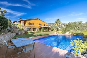 A house with a swimming pool, stone walls, and a patio with outdoor furniture. - Villa 'La Masia' with Mountain View, Wi-Fi and Air Conditioning (Calonge)