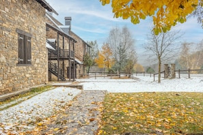Een stenen gebouw met een houten balkon, een met sneeuw bedekte grond en herfstbladeren.