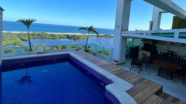 Una piscina con vista al océano, una terraza de madera y una zona de bar.