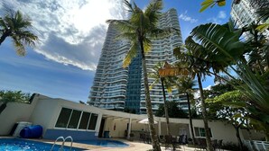 Un hotel con zona de piscina, mobiliario exterior y altos edificios al fondo.