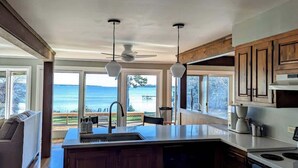 A kitchen with a large island, wooden cabinets, and a view of the ocean.