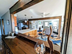A modern kitchen with wooden beams, a bar area, and a dining area with a chessboard.